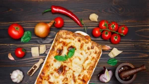 restaurant carqueiranne - photo d'un plat familliale de lasagne vu d'en haut sur une table en bois avec des ingrédients autour